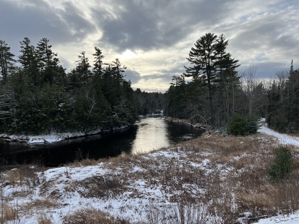 A snowy river running through the Maine woods near Two Falls Camps